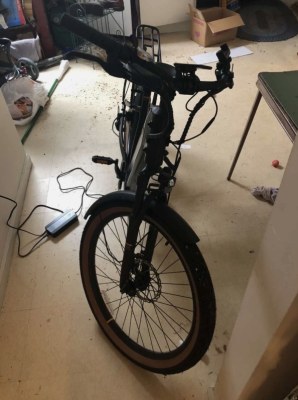 Vélo électrique noir, livré avec chargeur de batterie.